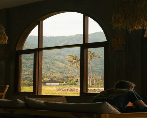 Person reading a book by the window on a rainy afternoon in Indonesia