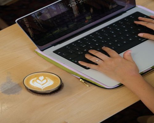 Person typing on laptop in an aesthetic coffee shop in Bandung